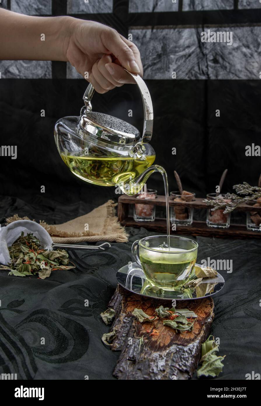 A Hot pandan leaf tea with indian marsh fleabane plant leaves and Safflower dried (Saffron substitute) is poured from the glass teapot into a glass wi Stock Photo