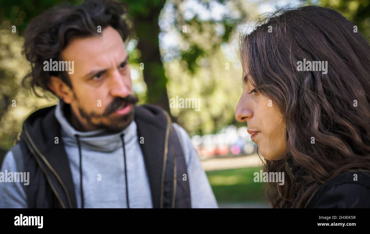 Bully and abuser, a jealous boyfriend abuses his girl girlfriend, verbally and physically threatens, yells at her and scares her, outdoor in public pa Stock Photo