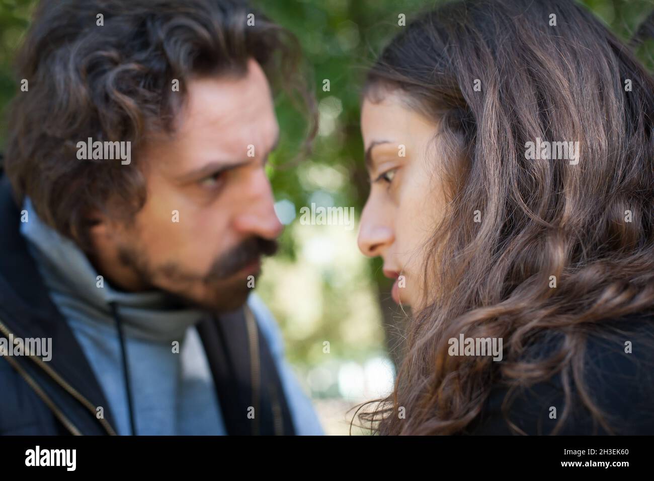 Bully and abuser, a jealous boyfriend abuses his girl girlfriend, verbally and physically threatens, yells at her and scares her, outdoor in public pa Stock Photo