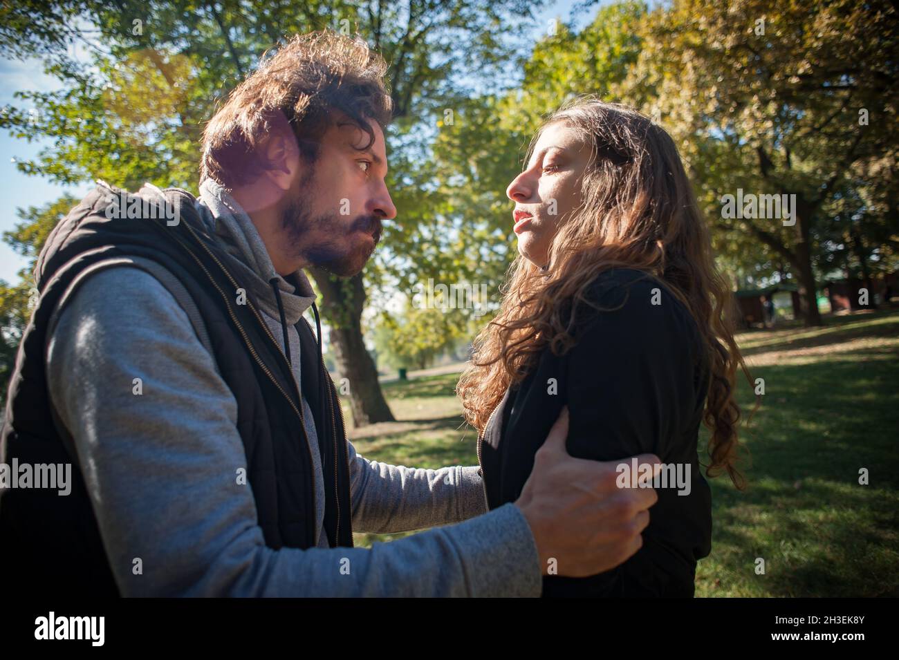 Bully and abuser, a jealous boyfriend abuses his girl girlfriend, verbally and physically threatens, yells at her and scares her, outdoor in public pa Stock Photo