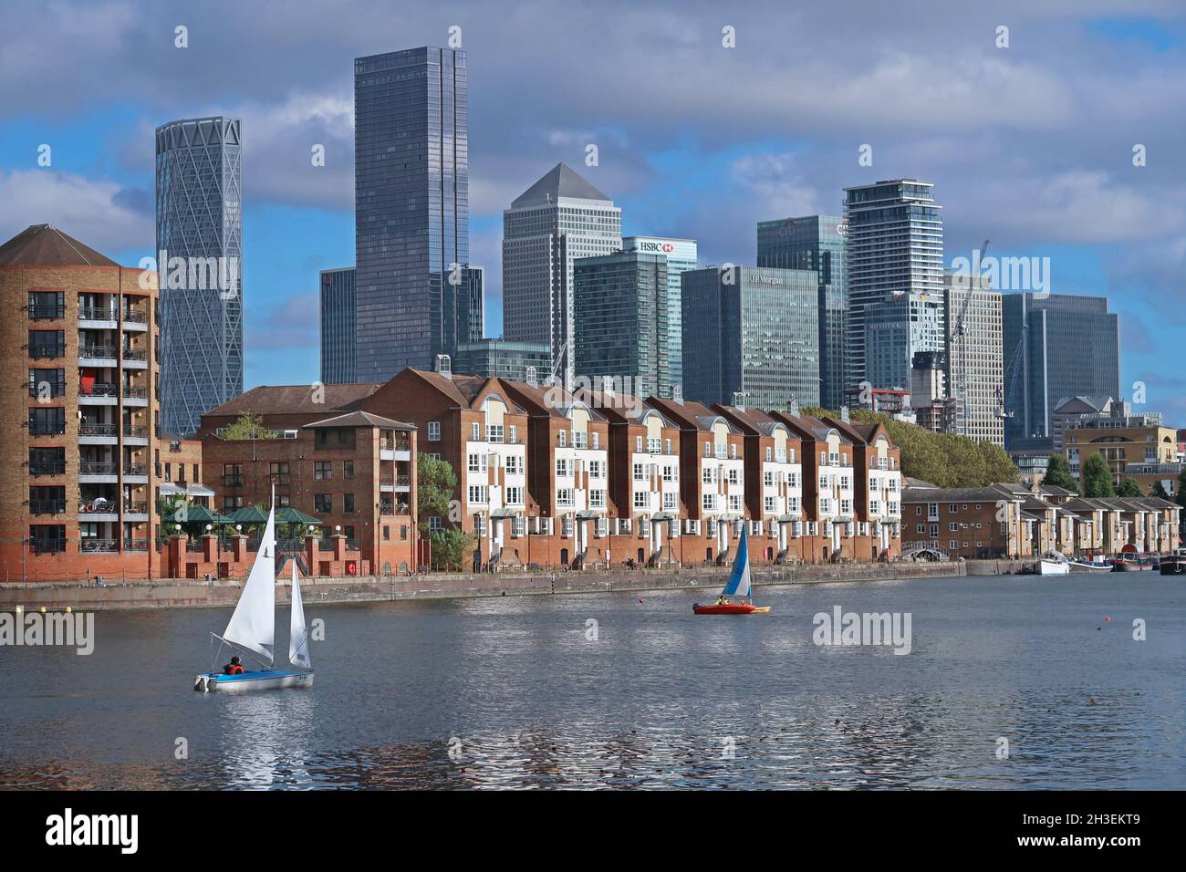 Sailing dingys from Greenland Dock Watersports Centre on Greenland Dock, part of the old Surrey Docks in Rotherhithe, London, UK. Canary Wharf beyond. Stock Photo