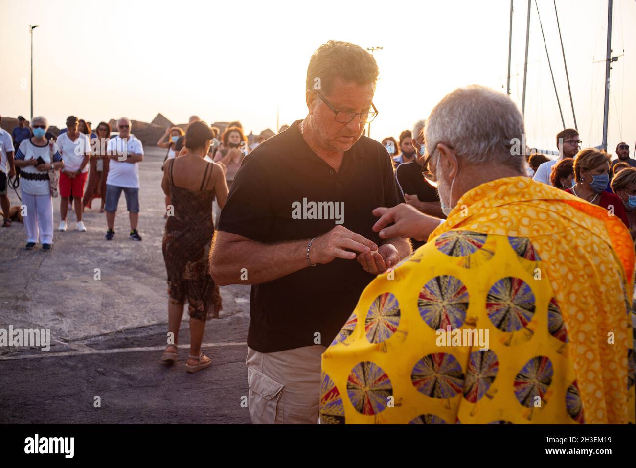 Linosa, Italy - July 25: Priest give host at faithful in the Procession of the Stella Maris during the religious patronal feast of the Madonna of the Stock Photo