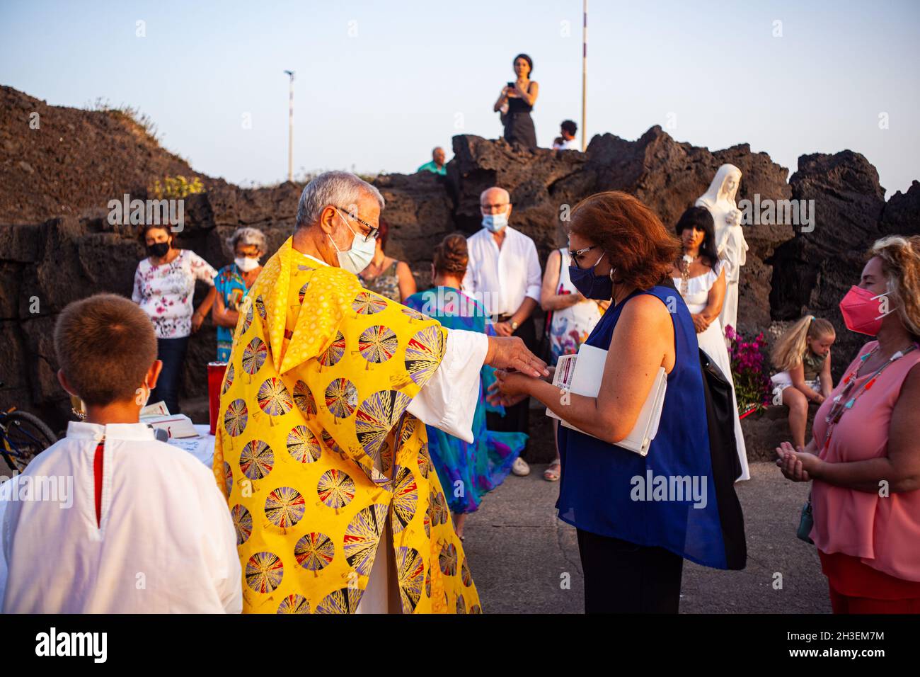 Linosa, Italy - July 25: Priest give host at faithful in the Procession of the Stella Maris during the religious patronal feast of the Madonna of the Stock Photo