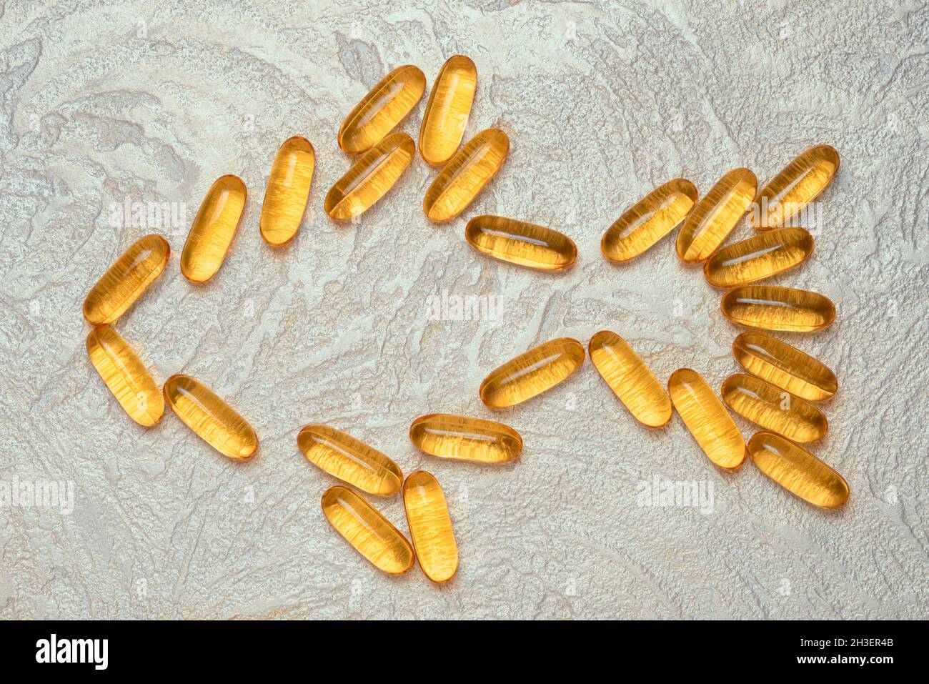 Omega3 capsules in fish shape silhouette on a cement background. EPA and DHA are essential fatty substances that our bodies need on a daily basis. Stock Photo