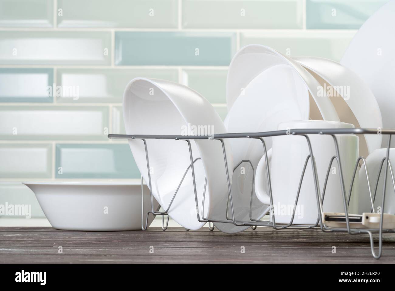 Dish rack with clean dry dishes on kitchen counter Stock Photo