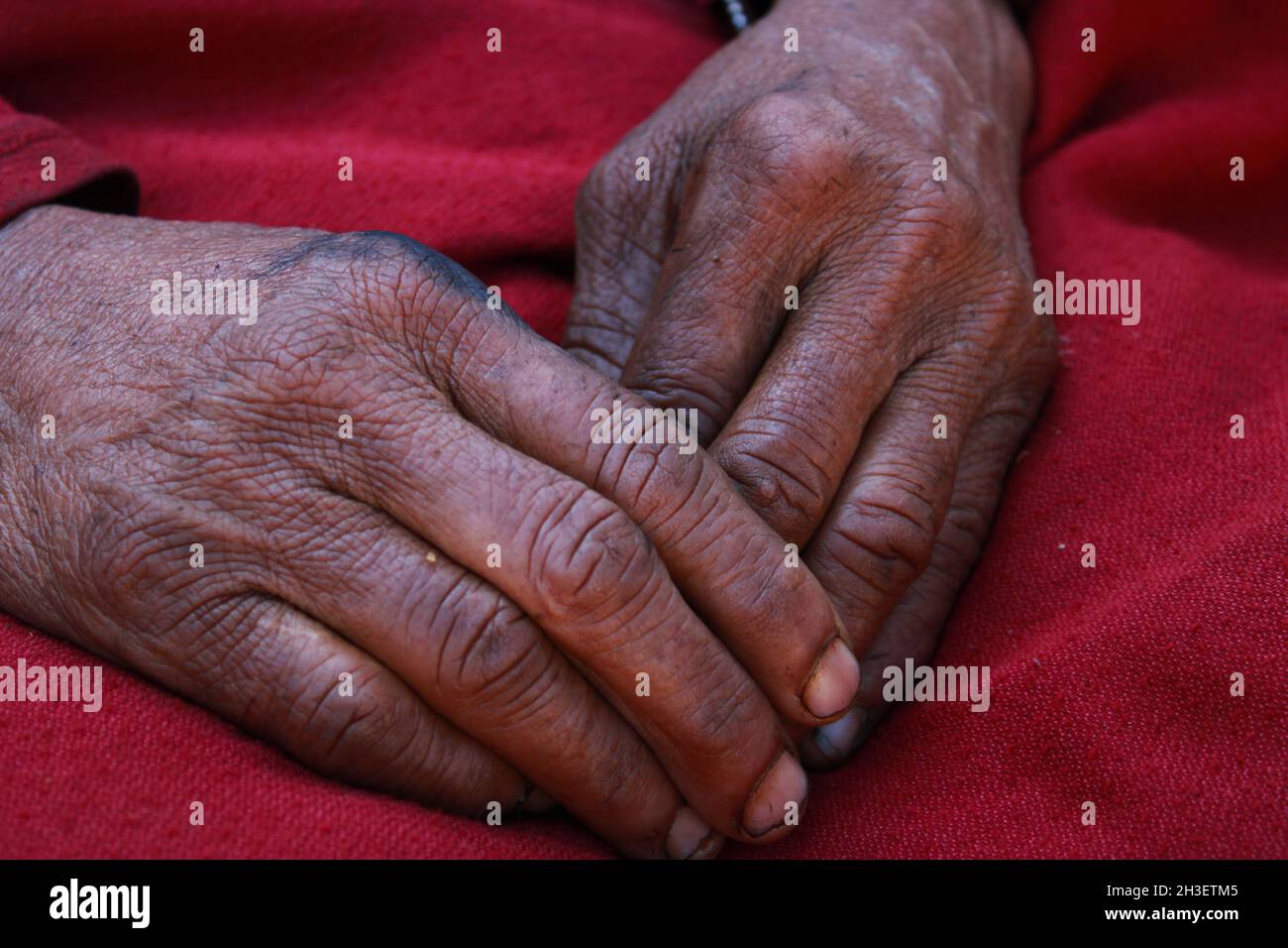 hand of old Asian hardworking women on red clothes. Stock Photo