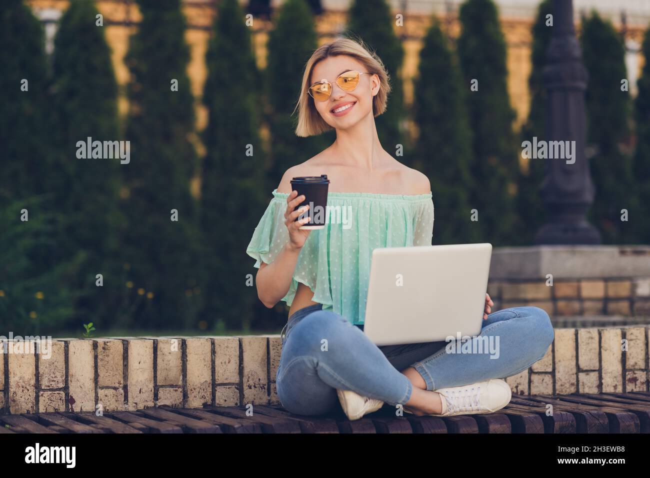 Full size photo of lovely millennial blond lady drink coffee write laptop wear green blouse spectacles outsite in park Stock Photo