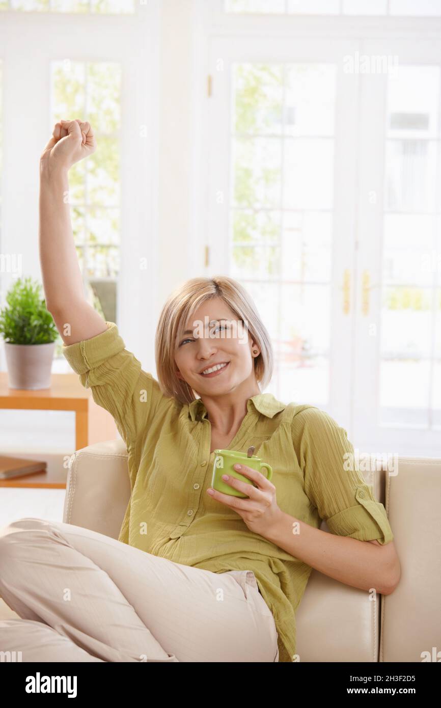 Woman drinking tea and stretching at home Stock Photo