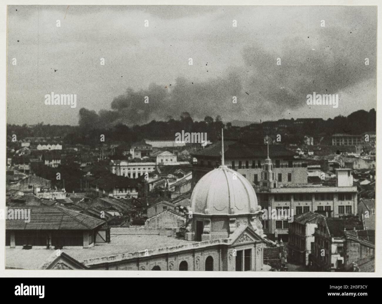 A vintage photo circa February 1942 showing smoke rising above the city of  Singapore during an air raid by the Japanese airforce during the invasion of Malaya and the fall of Singapore. Stock Photo