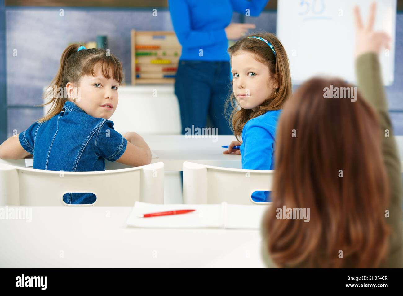 Schoolgirls sitting at desk in classroom Stock Photo - Alamy