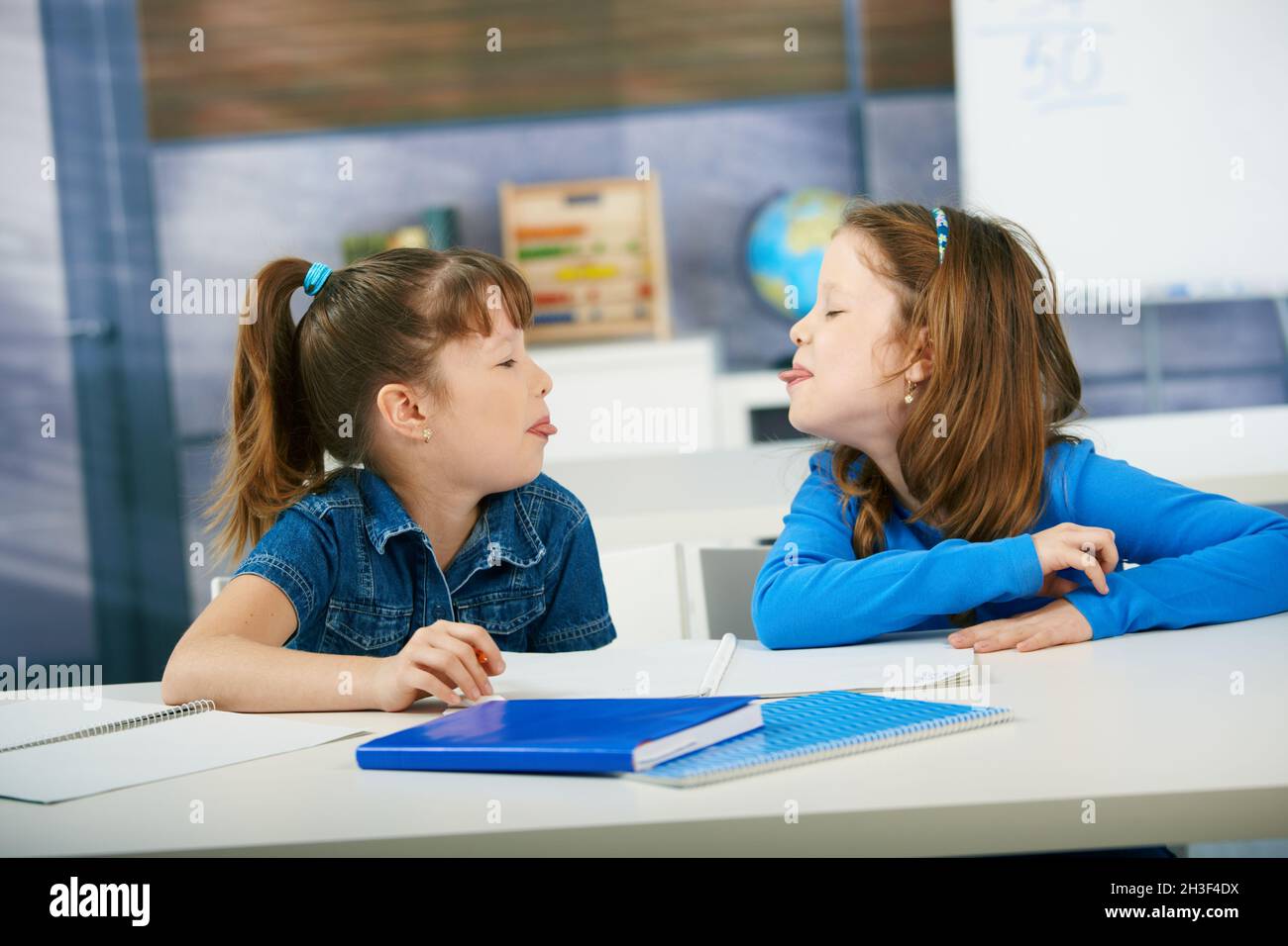 Children sticking tongue in classroom Stock Photo