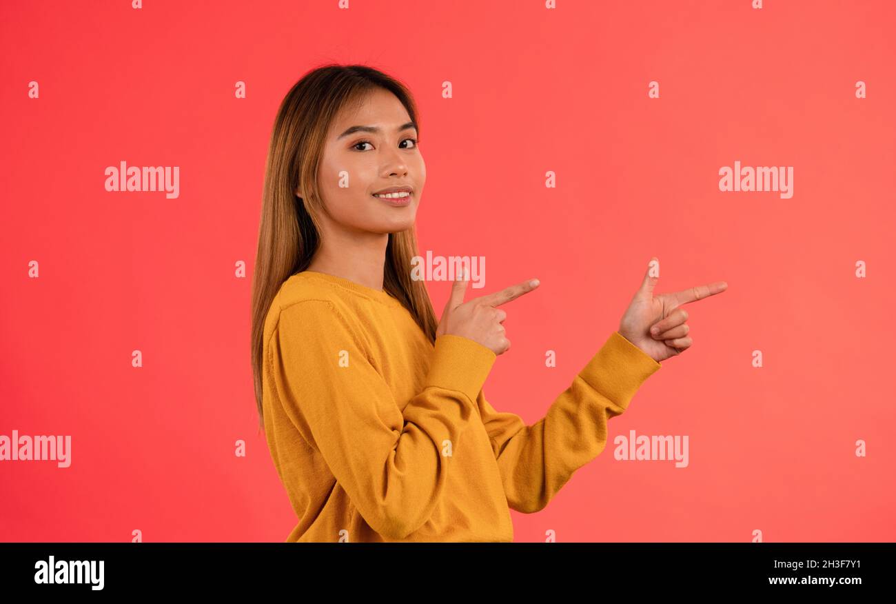 Portrait of young attractive asian girl pointing on side Stock Photo