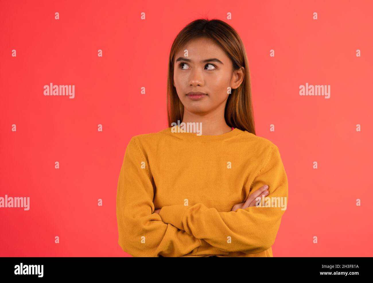 Young attractive grumpy asian girl rolling her eyes with arms crossed Stock Photo