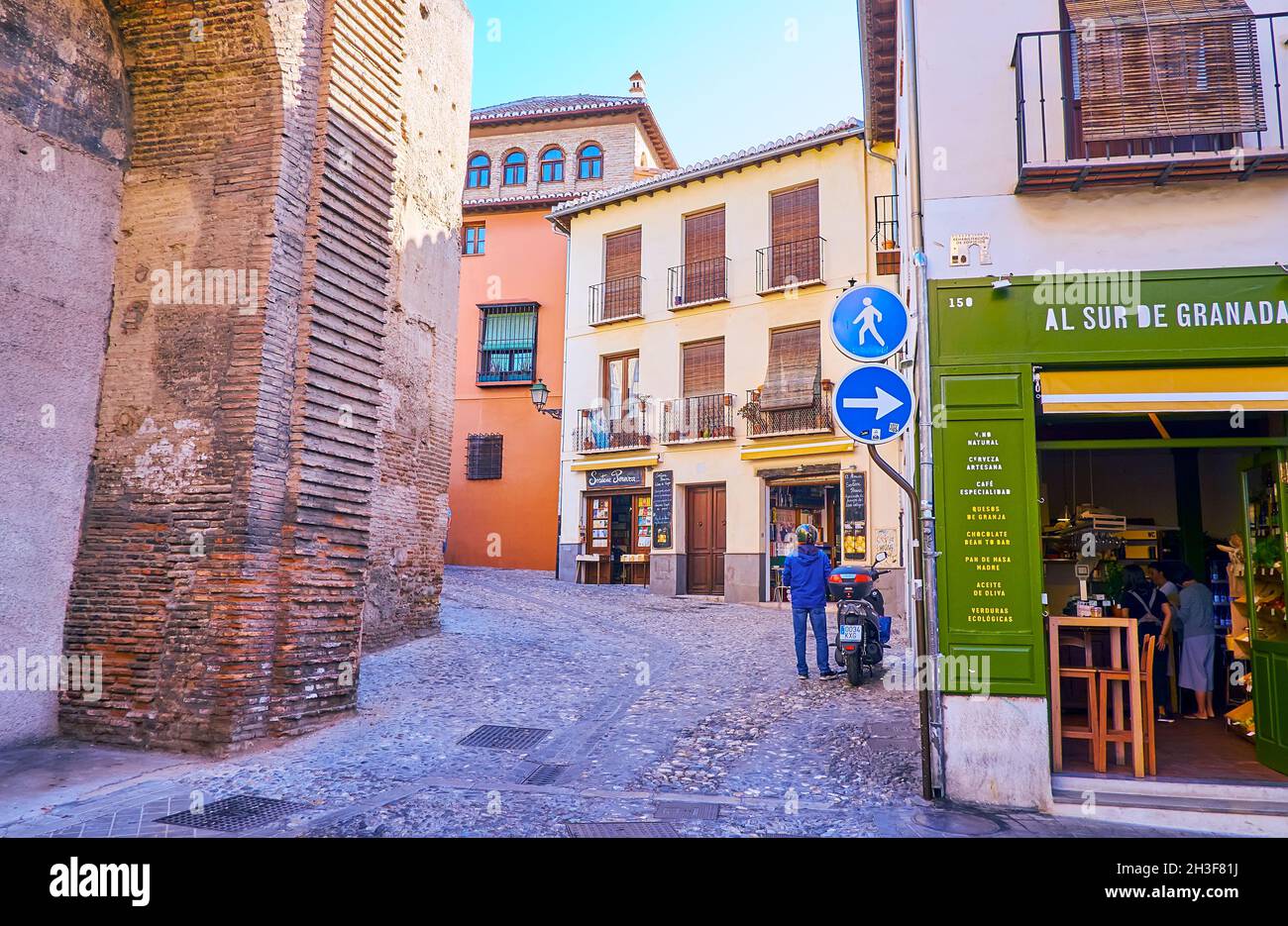 GRANADA, SPAIN - SEPT 27, 2019: The narrow curved Horno de la Merced street of Albaicin historic neighborhood with historic houses, cafes and wall of Stock Photo