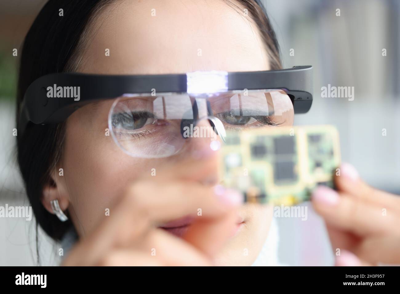 Master repairman in goggles looking at computer microchip Stock Photo