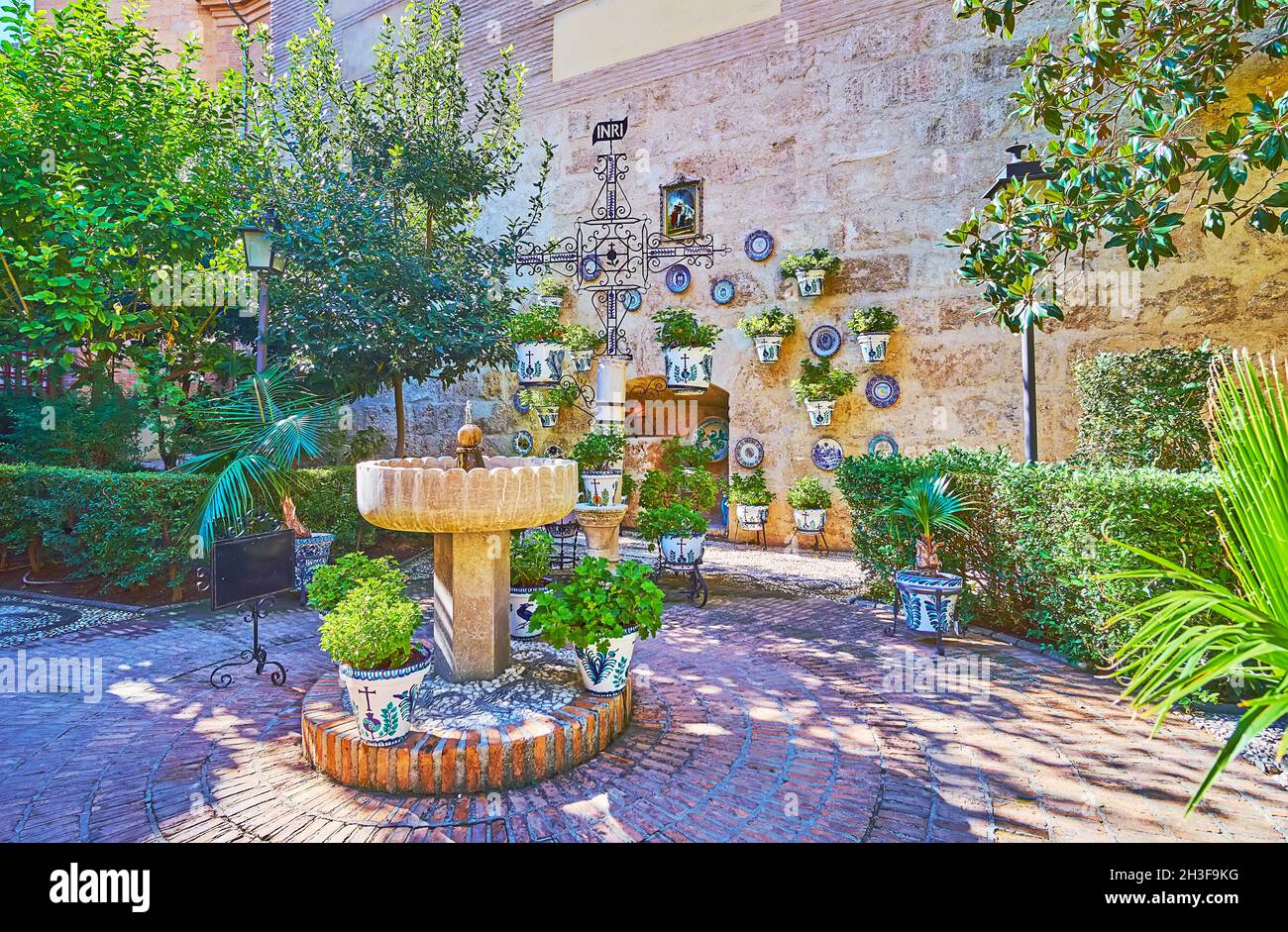 The drinking fountain and flowers in colorful ceramic pots in garden of San Juan de Dios Basilica, Granada, Spain Stock Photo