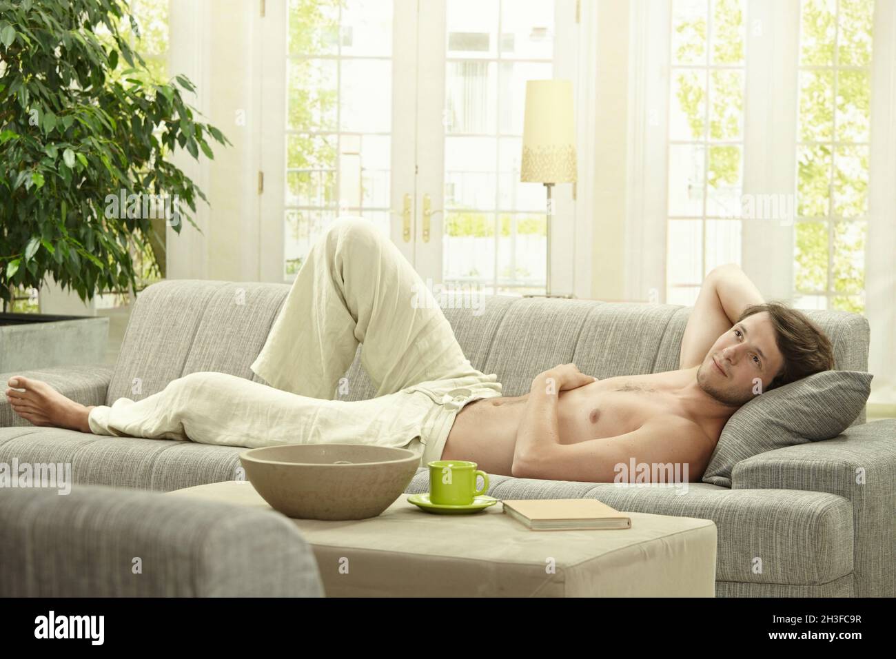 Young man resting on couch Stock Photo - Alamy