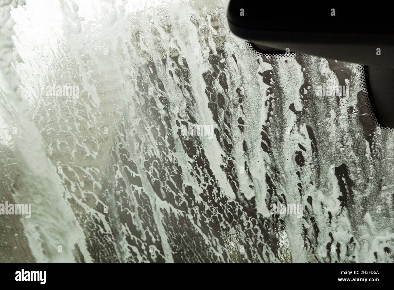 Winchester, Hampshire, UK. 2021. Drivers eye view of soap suds and water during a car wash Stock
