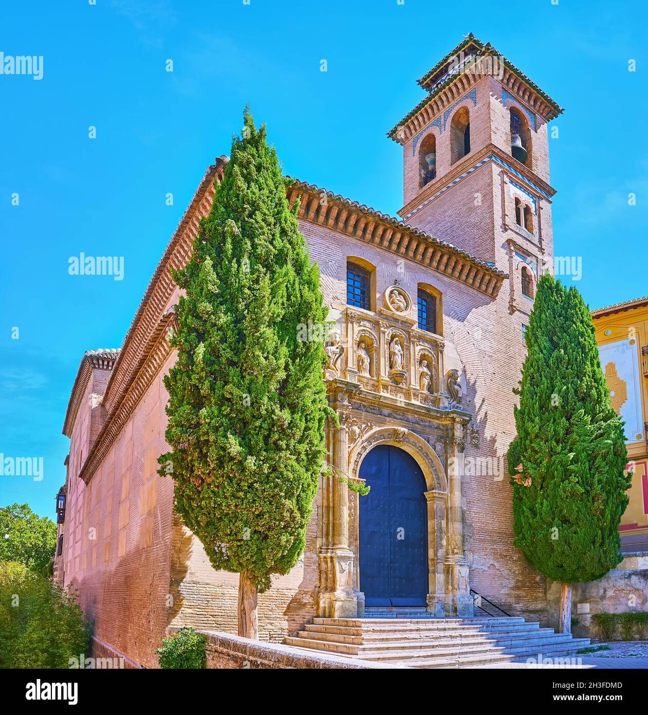 The facade of medieval brick San Gil and Santa Ana Church, decorated with impressive carved stone door frame with sculptures, Granada, Spain Stock Photo