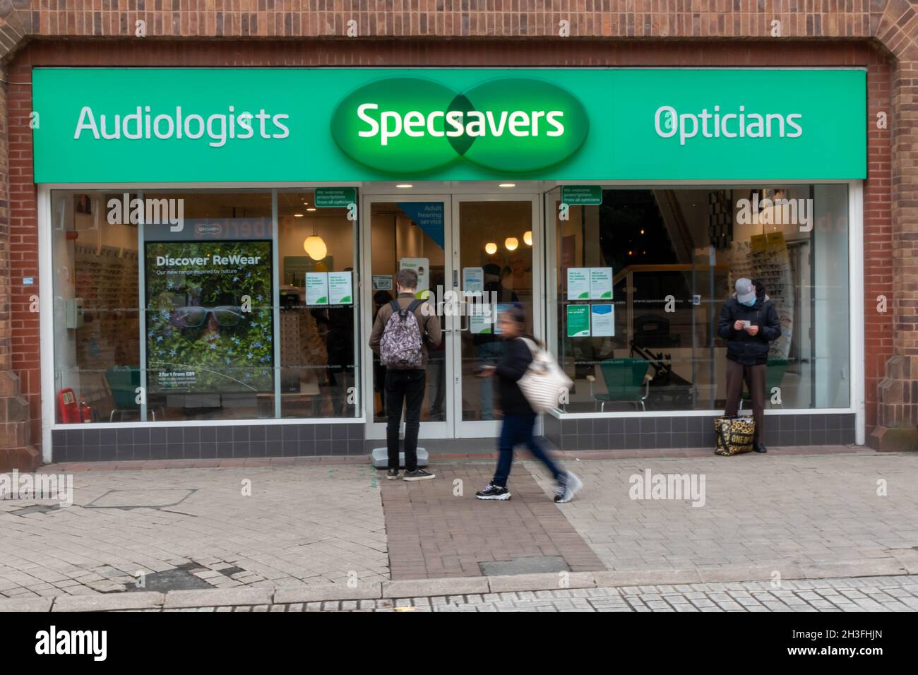 High Wycombe, England - October 22nd 2021: People outside a Specsavers shop. They are a chain of opticians and audiologists, Stock Photo