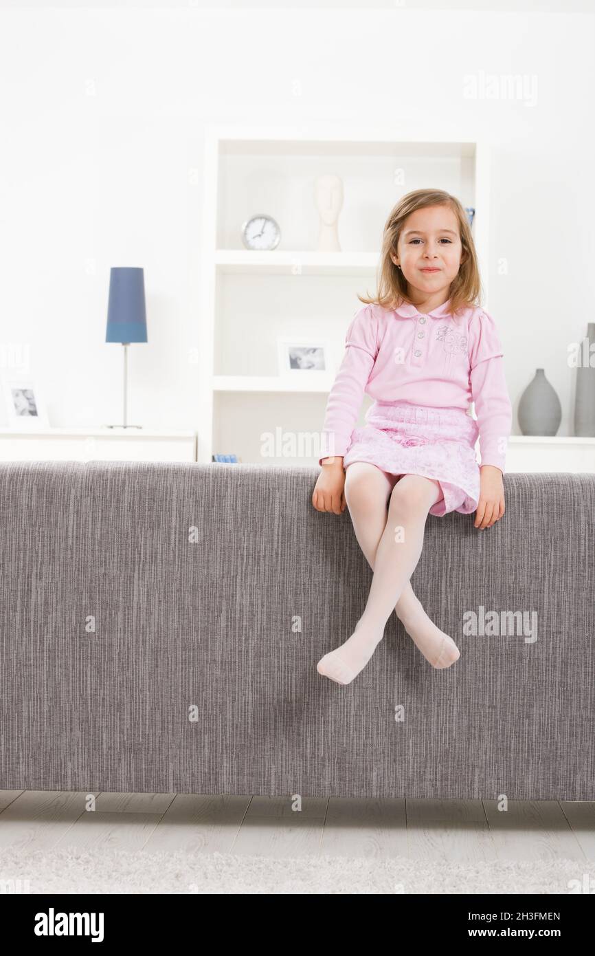 Girl in pink sitting on couch Stock Photo