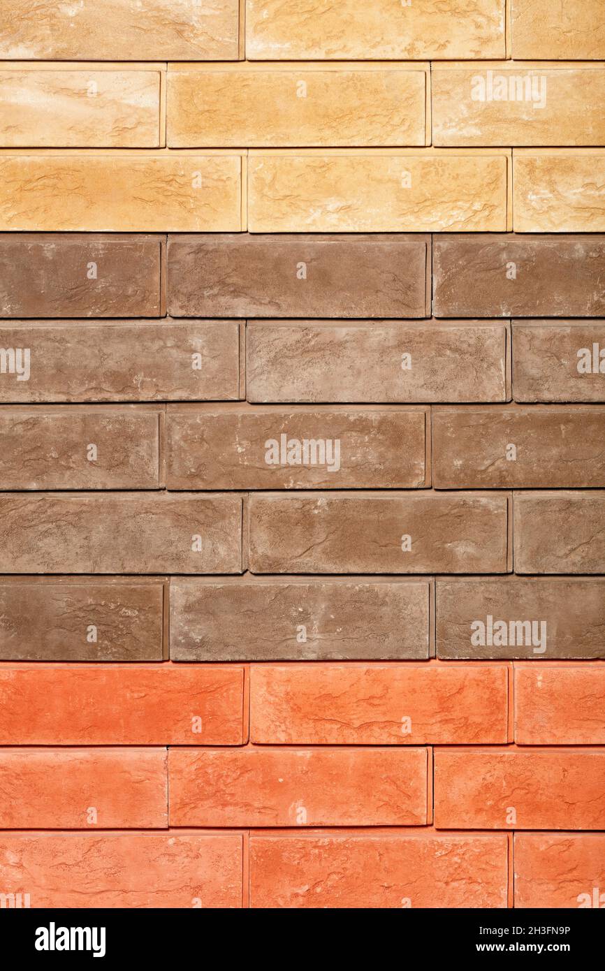 Brick tile wall texture with splashes of orange, brown and beige. Vertical image, closeup Stock