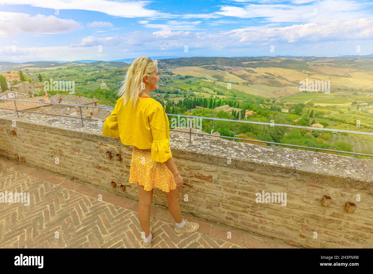 Lifestyle tourist woman on top view of terraced vineyards in Tuscany village Montepulciano in Italy. Famous for Rosso wine of Montepulciano. Vines Stock Photo