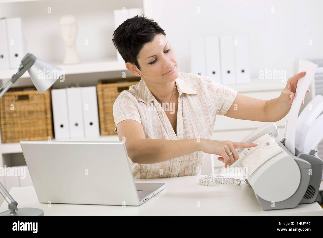 Woman using fax machine Stock Photo