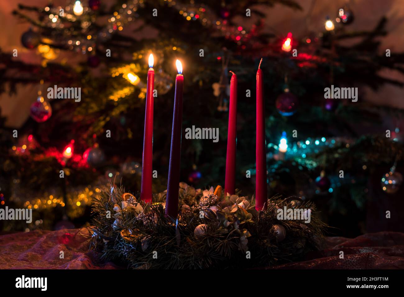 burning 2nd advent candle with illuminated christmas tree in
