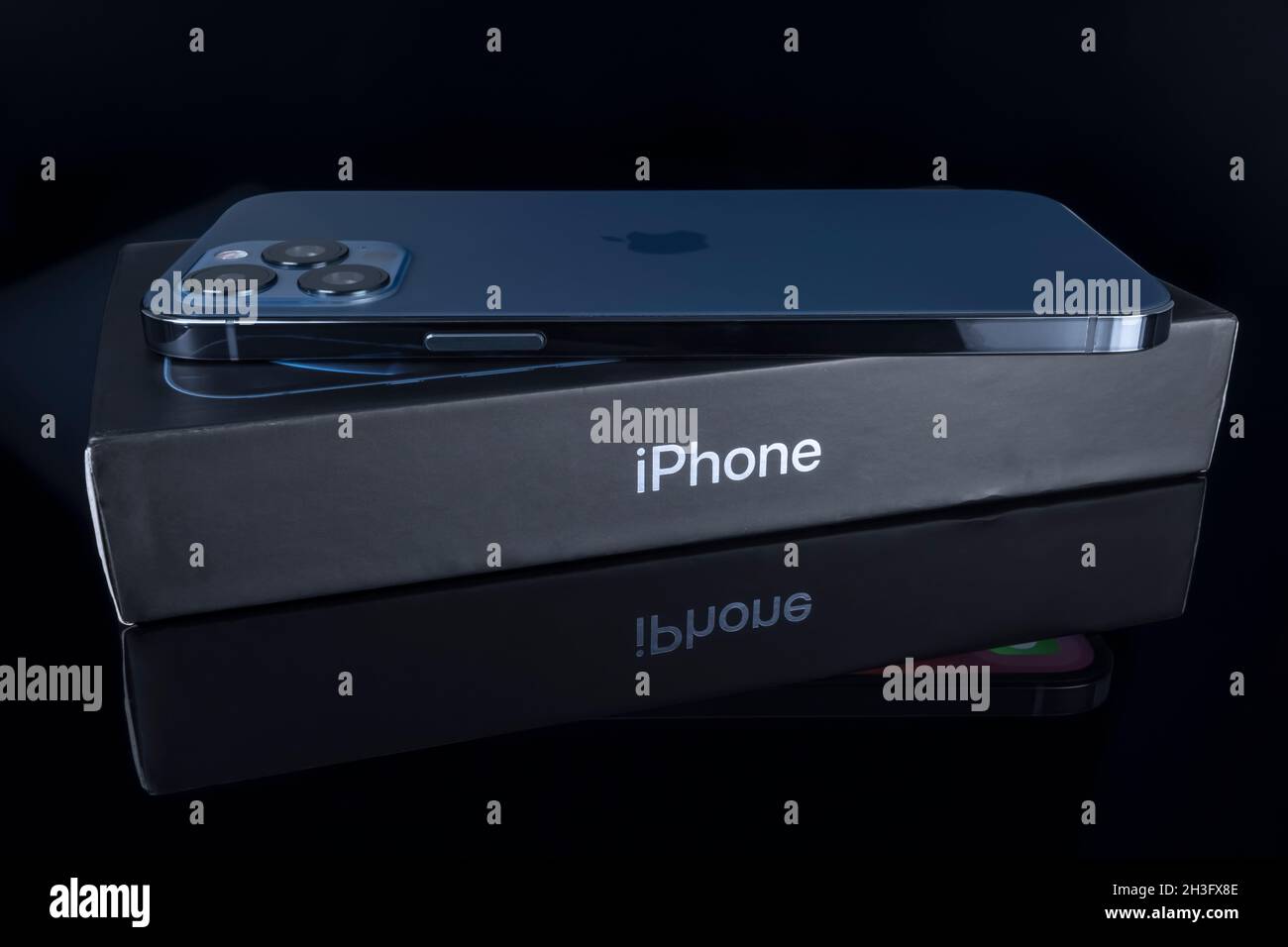 Galati, Romania - October 14, 2021: Studio shot of new Apple iPhone 12 Pro Max blue color over iPhone box. Isolate on black background. Illustrative e Stock Photo