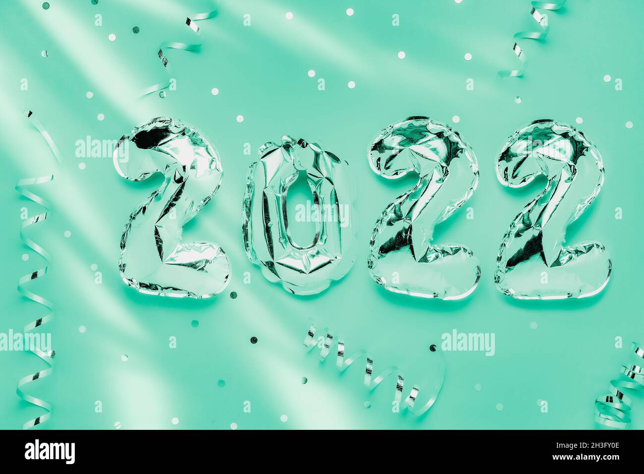 Foil balloons in form of numbers 2022. Silver color air balloons on green background. Flat lay with copy space Stock Photo