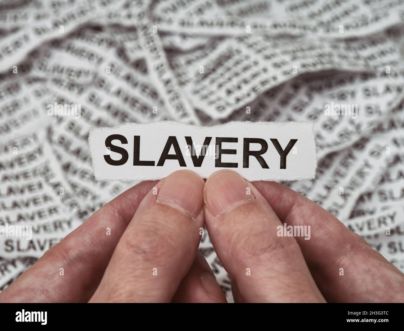 A man holding a torn piece of paper with the word Slavery on it in his