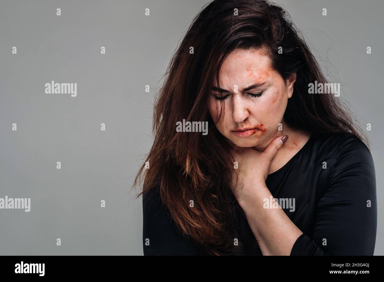 a battered woman in black clothes on an isolated gray background
