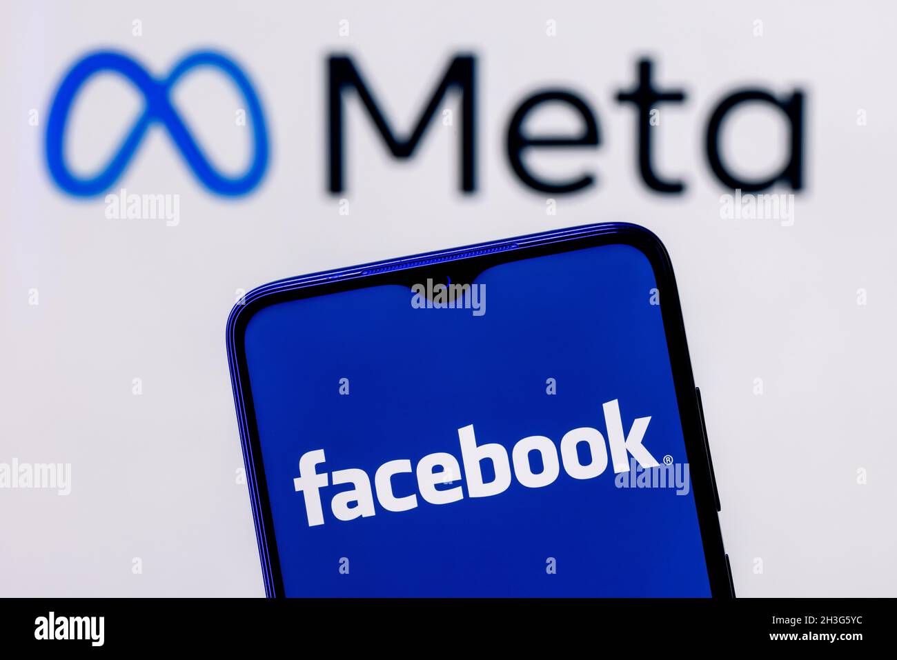 Facebook changes its name to Meta. Smartphone with Facebook logo on the background of Meta logo. Stock Photo