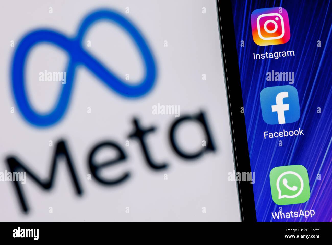 Facebook changes its name to Meta. Smartphone with Facebook, Whatsapp and Instagram app icon on the background of Meta logo. Stock Photo