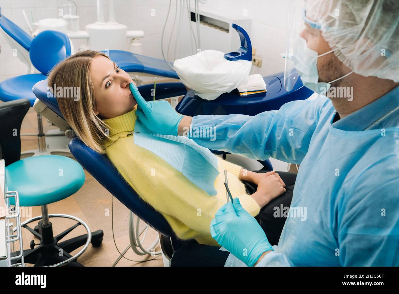 a dentist wearing a protective mask sits down next to the patient and