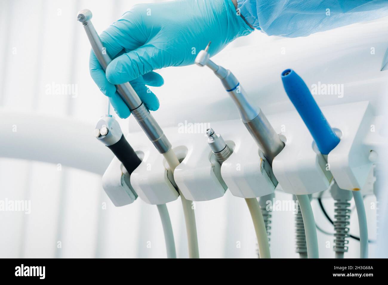 a dentist wearing gloves in the dental office holds a tool before