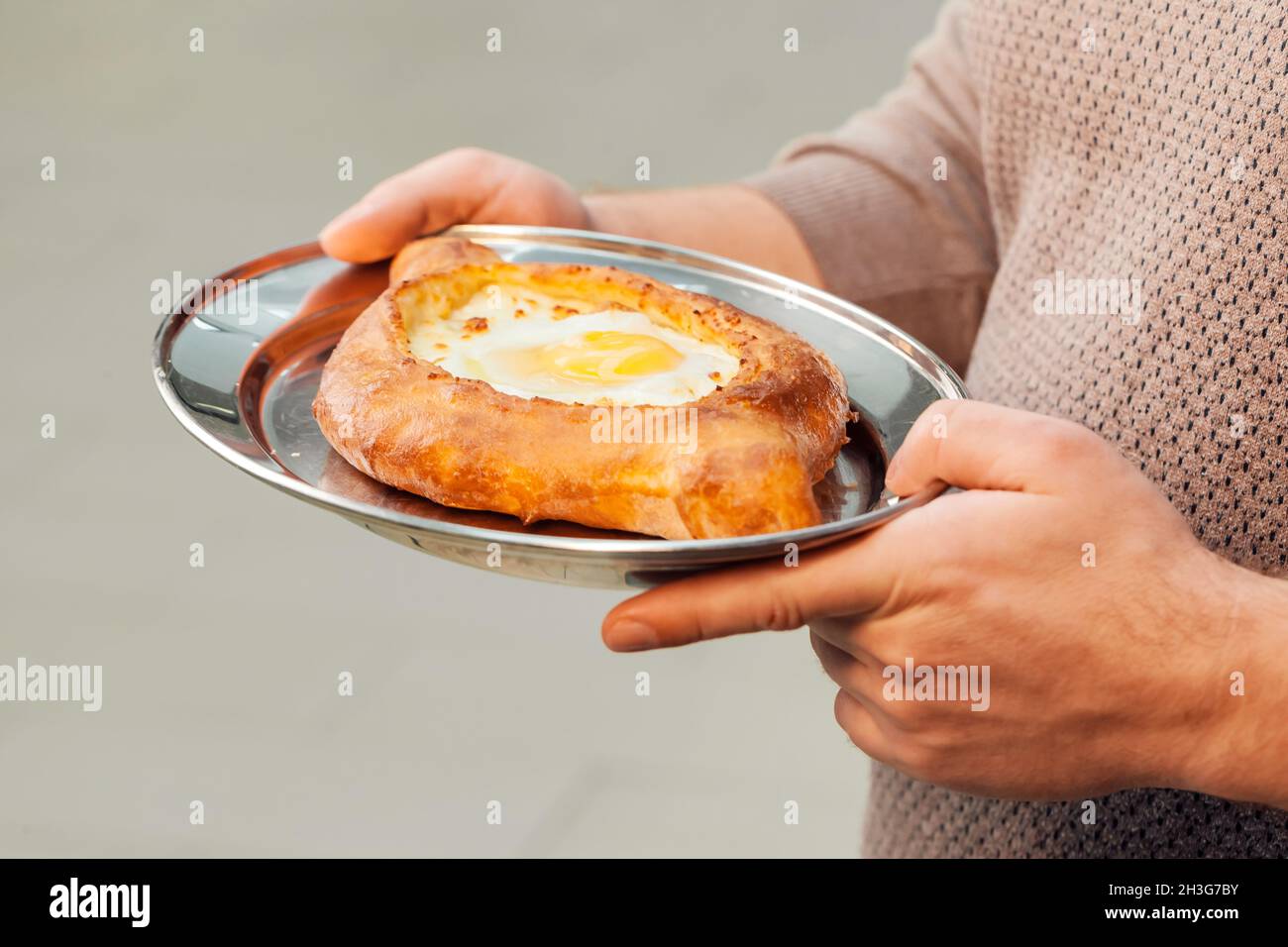 https://c8.alamy.com/comp/2H3G7BY/closeup-of-male-hands-holding-a-tray-with-prepared-khachapuri-2H3G7BY.jpg