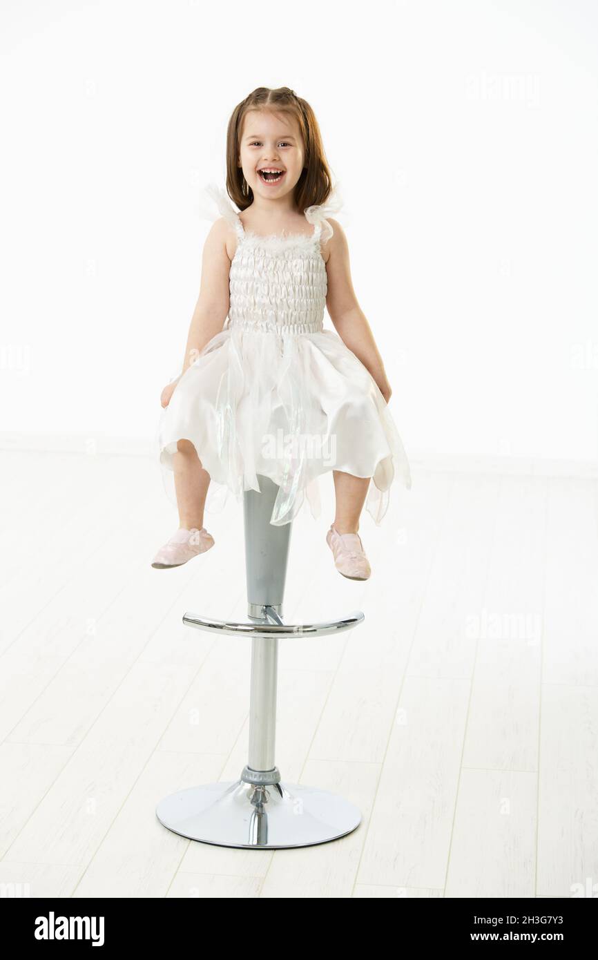 Happy little girl sitting on chair Stock Photo - Alamy