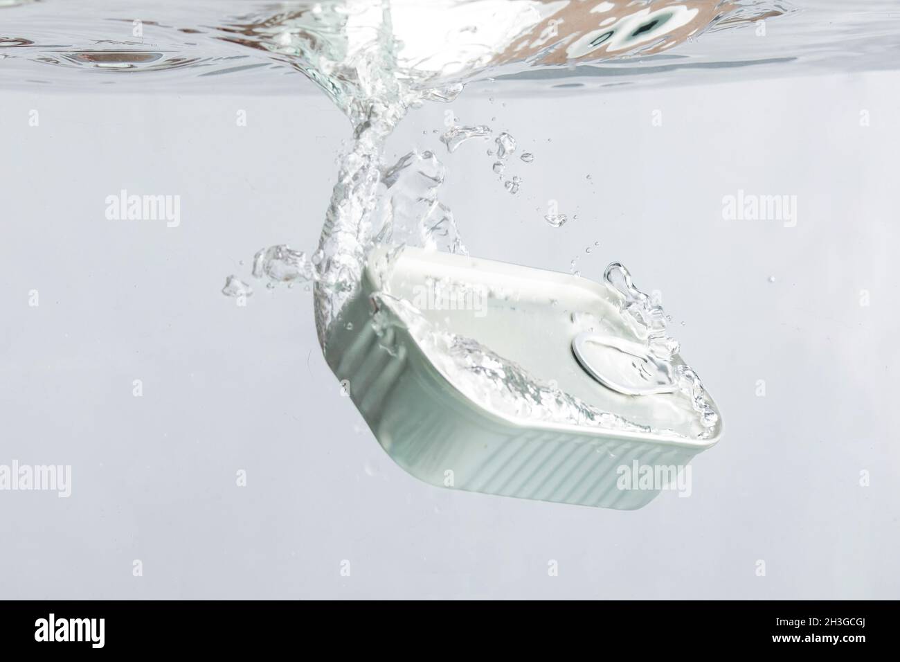 Can of sardines falling in the water on a light background Stock Photo
