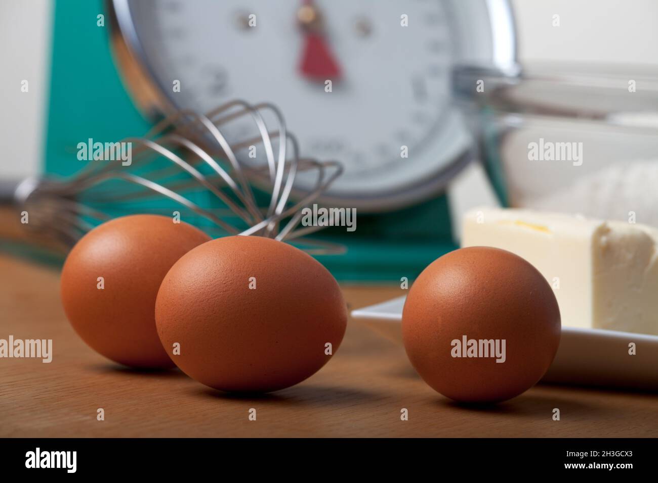 Eggs and a whisk on a wooden table Stock Photo