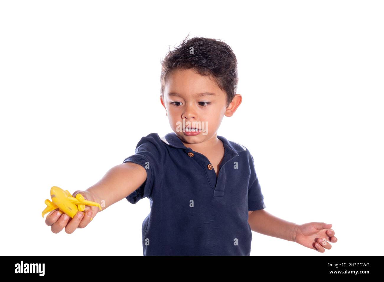 Boy playing with toy plane, isolated on white background. Latin child playing in front of camera. Stock Photo