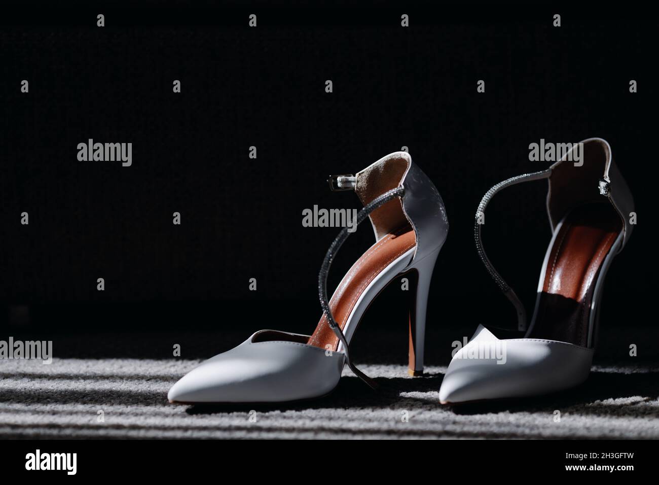 Elegant white female shoes on a dark background Stock Photo