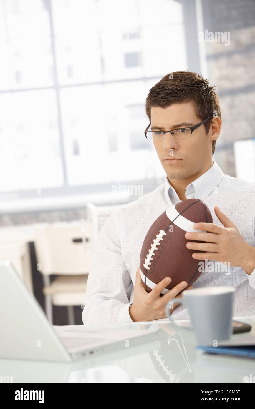 Determined businessman in office with football Stock Photo