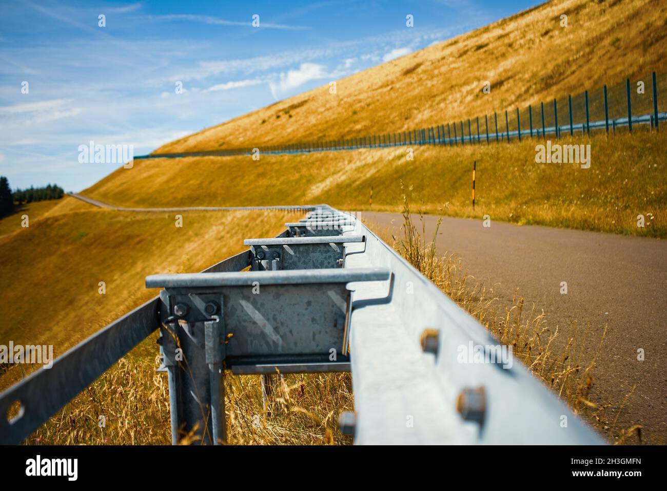 Metal railing on a trail through bright yellow hills Stock Photo - Alamy