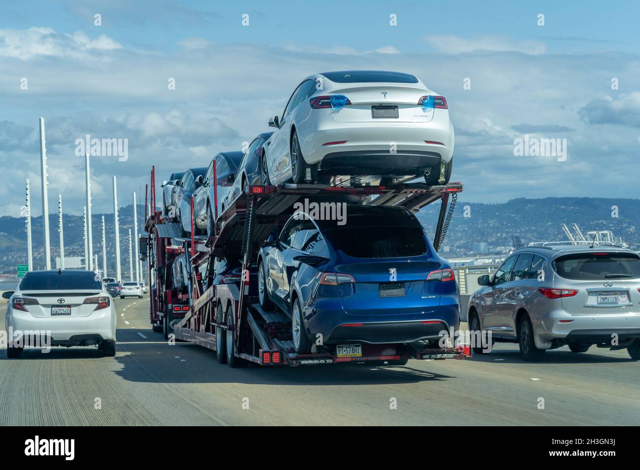 SAN FRANCISCO, UNITED STATES - Mar 19, 2021: New Tesla cars being transported from a factory on a car hauler on a San Francisco Bay Bridge Stock Photo
