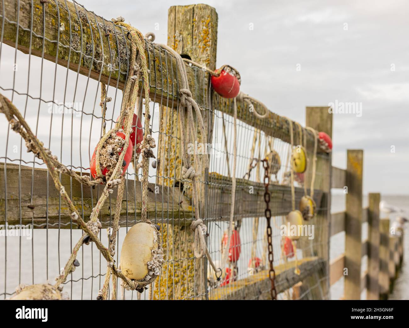 Fishing net with red floats hanging on a fence waiting for better weather.  Side view, selective focus, blurred background, nobody Stock Photo - Alamy
