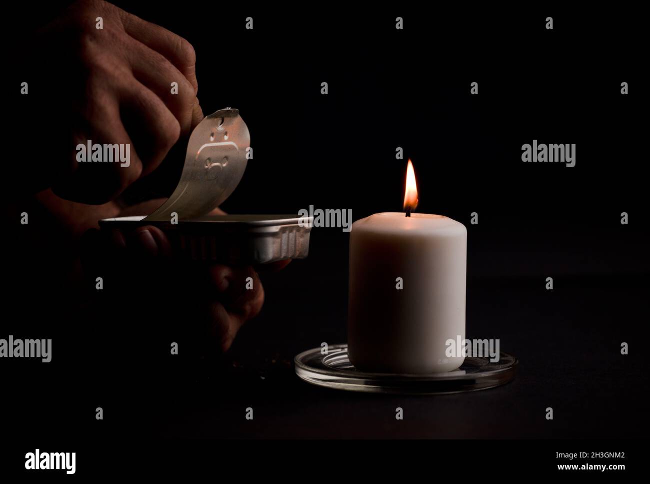 concept of energy blackout, lit candle, with can of preserves in man's