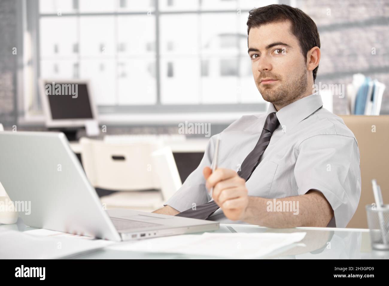 Young man sitting at desk using laptop Stock Photo