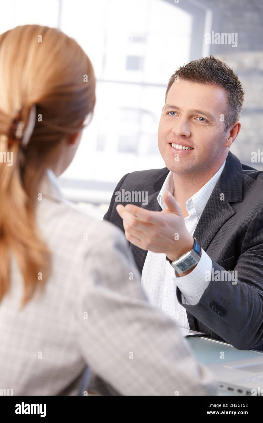 Male manager interviewing female candidate smiling Stock Photo